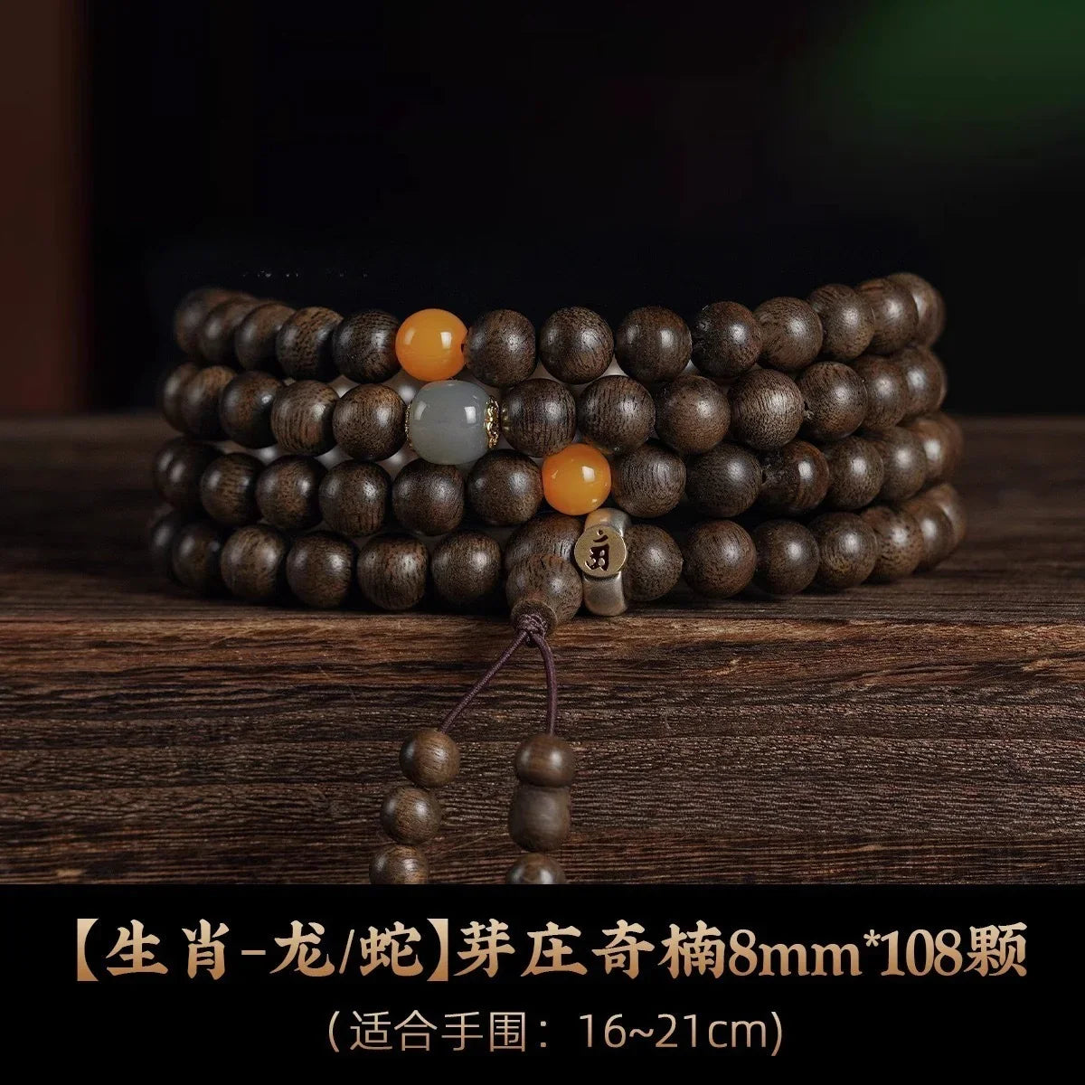 Dark wooden 108-bead mala bracelet with orange and gray beads on rustic wood surface