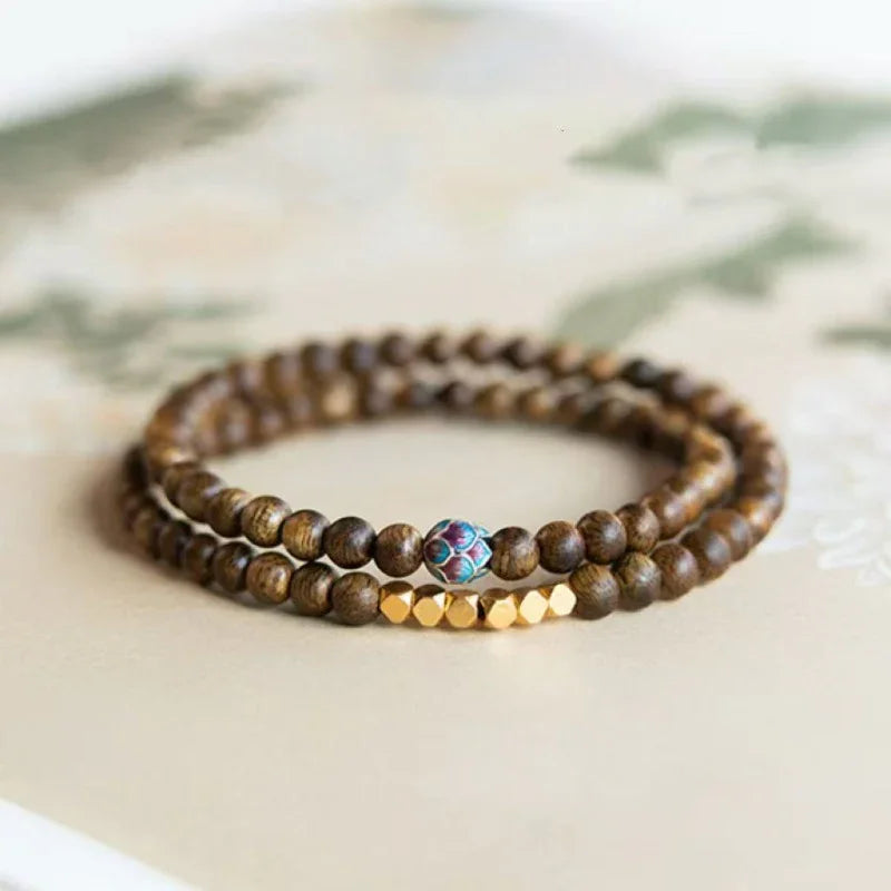 Double wrap wooden bead bracelet with gold faceted beads and a single colorful decorative bead