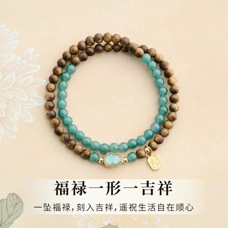 Two beaded bracelets with brown wooden and green jade stones on beige background with Chinese text