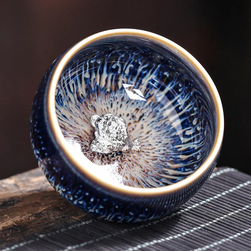 Blue ceramic bowl with intricate pattern and a small silver nugget inside on wooden surface