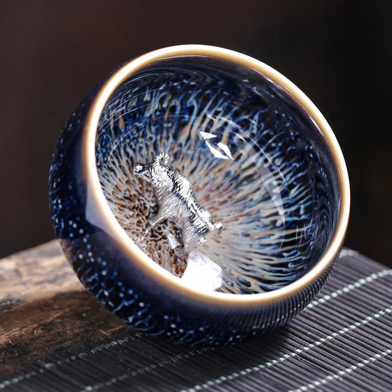 Blue ceramic bowl with intricate inner glaze and silver bear figurine inside on wooden surface