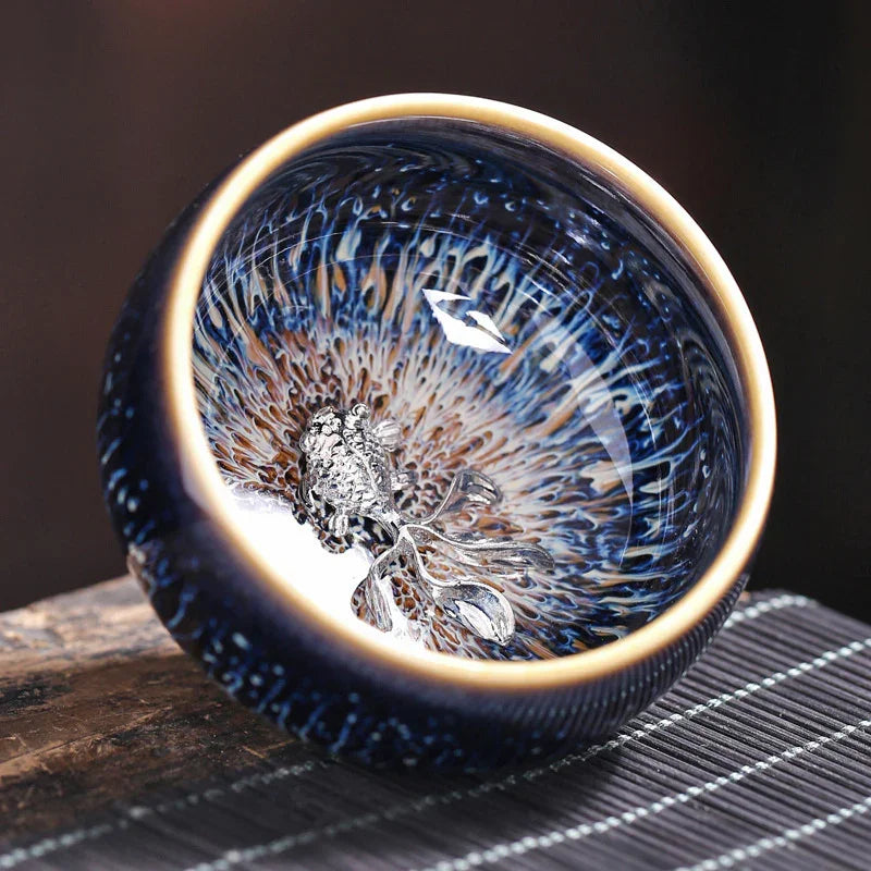 Close-up of a dark blue ceramic bowl with intricate patterns and a silver decorative element inside, placed on a textured surface
