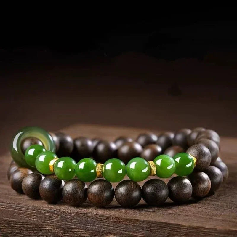 Close-up of wooden bead bracelet with shiny green jade beads and gold spacers on wooden surface