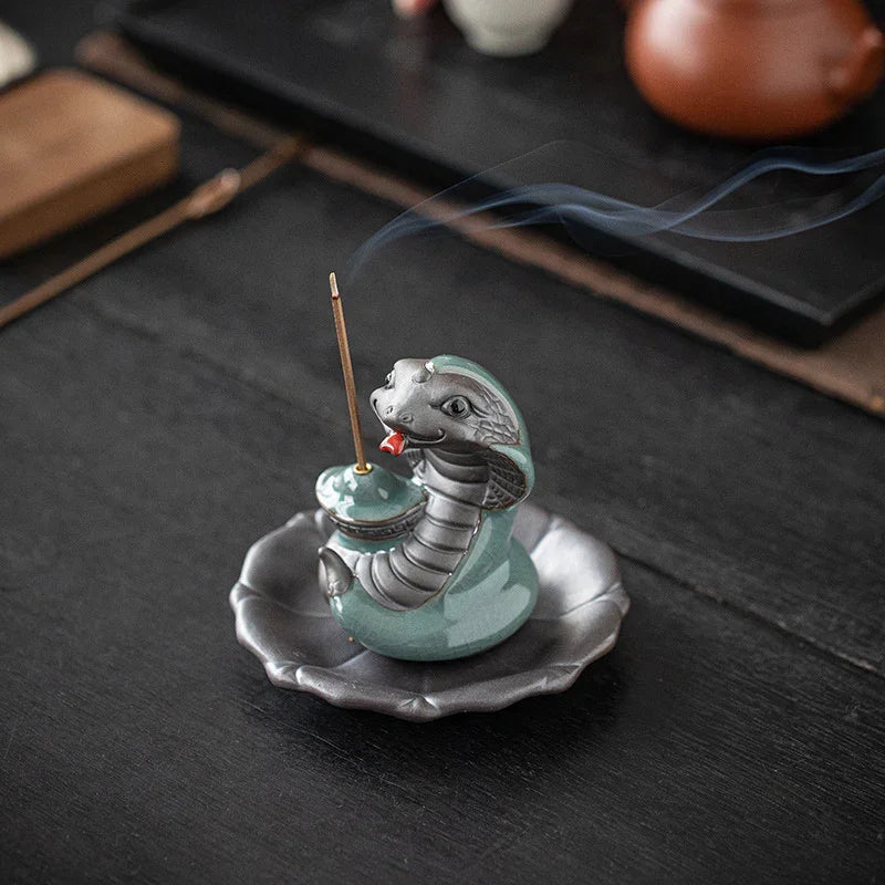 Ceramic snake-shaped incense holder with smoke on dark wooden table