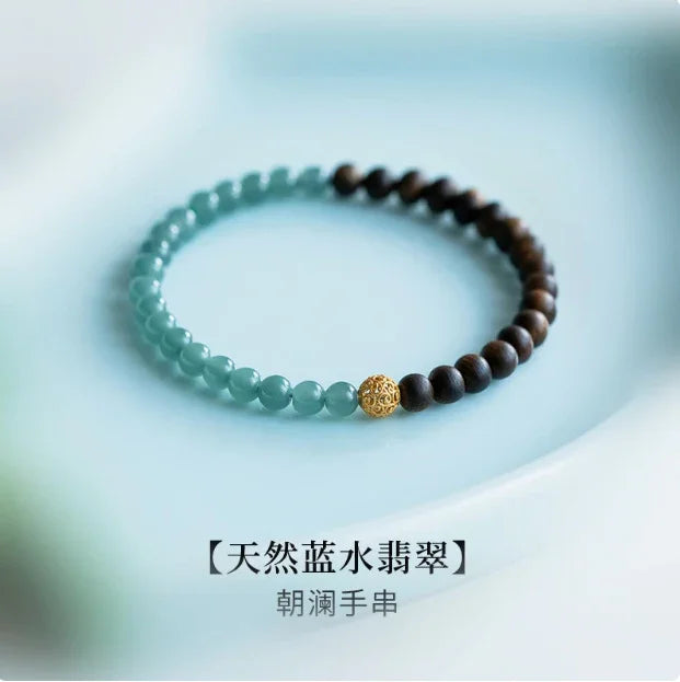 Round beaded bracelet with aquamarine and dark wooden beads separated by a decorative gold bead