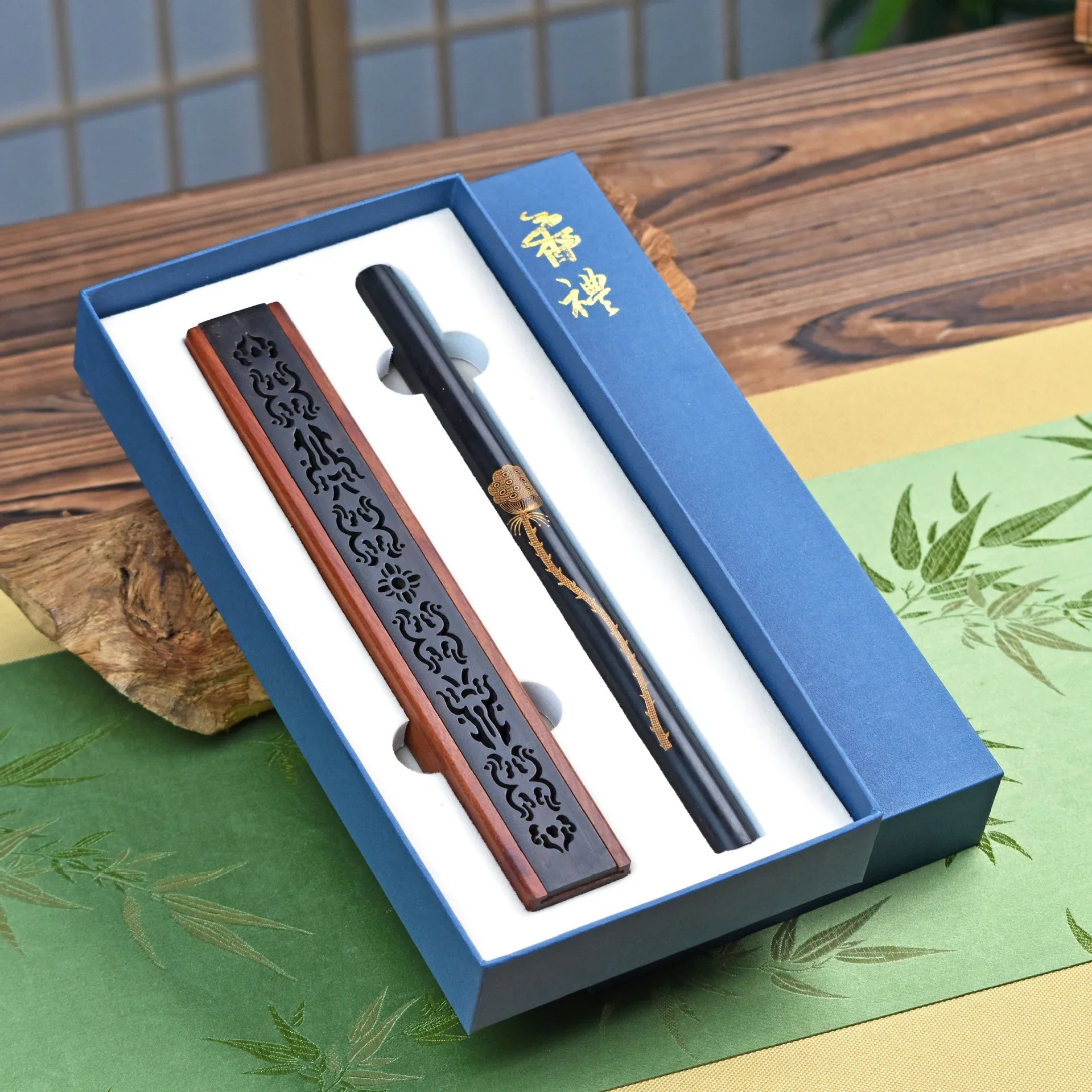 Elegant black and wooden incense holder and stick in a blue gift box on wooden table