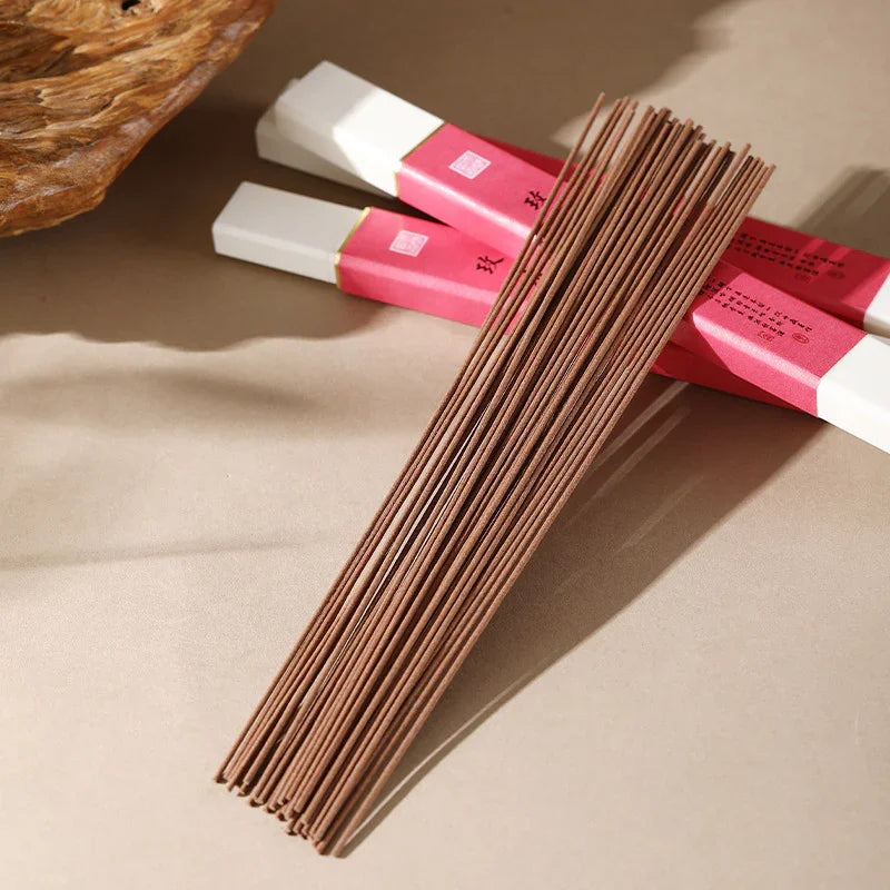 Brown incense sticks with two pink and white packaging boxes on beige surface
