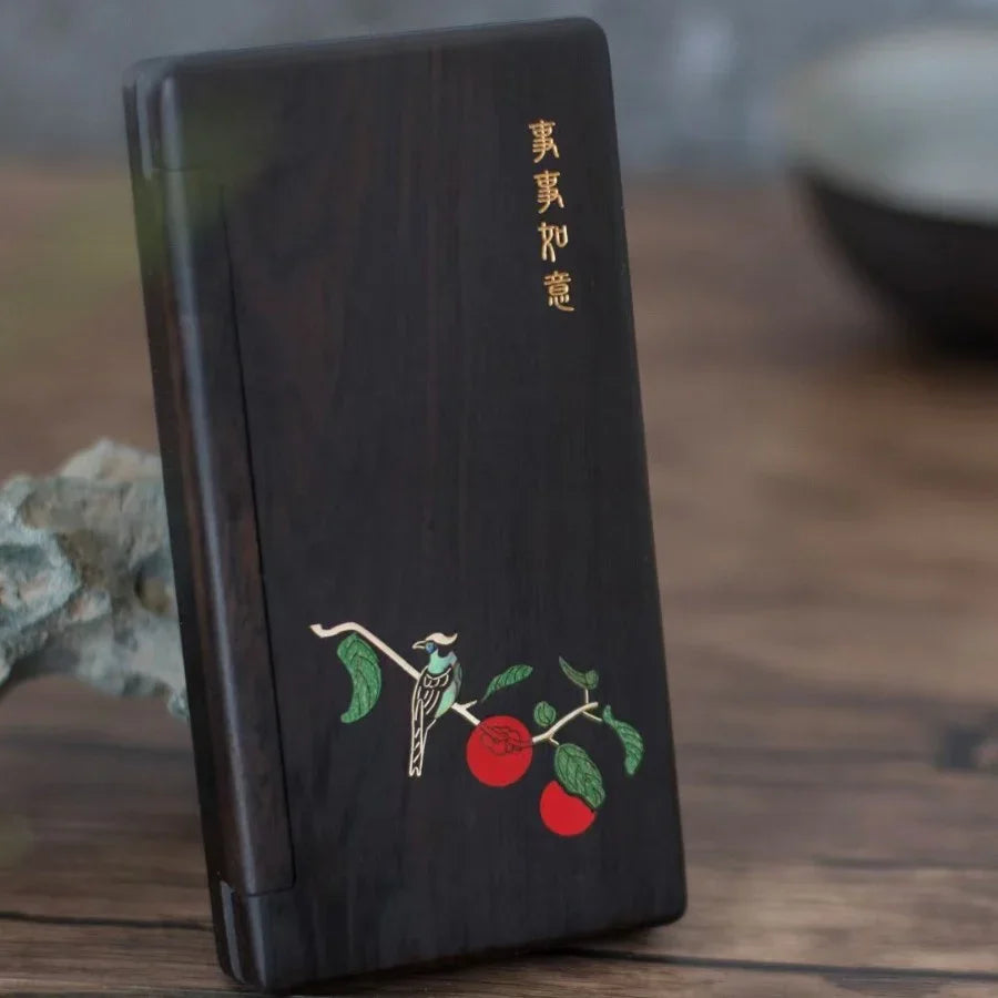 Dark wooden phone case with carved bird, red fruit design, and gold Chinese characters