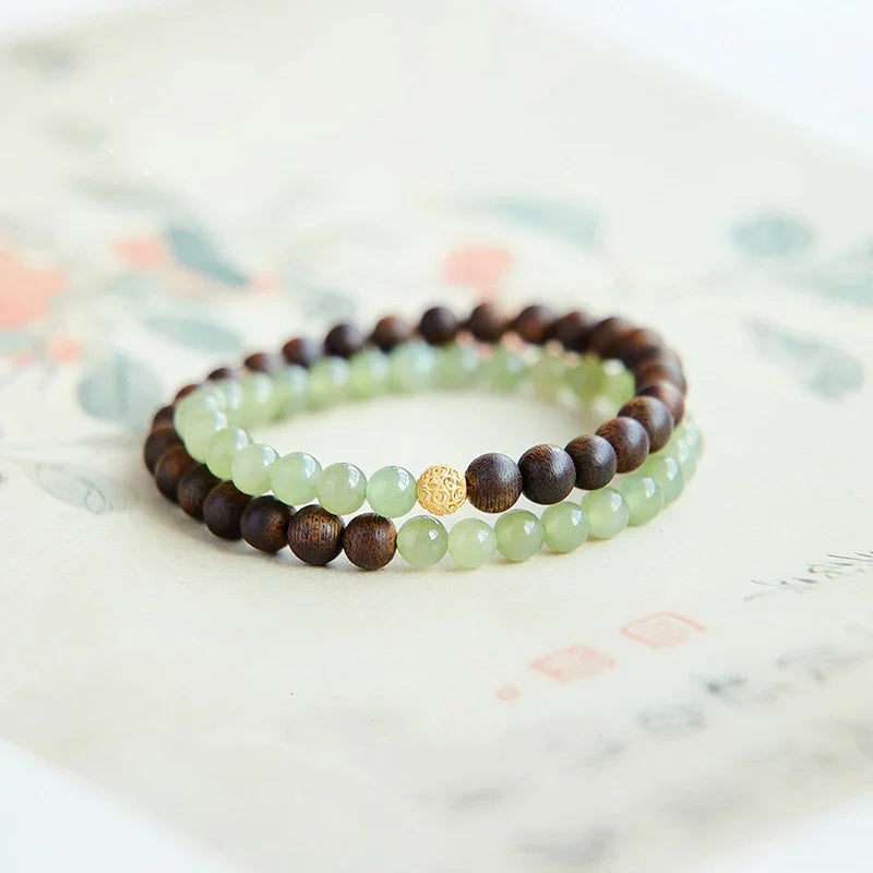 Double-layer bracelet with green jade and dark wooden beads featuring a decorative gold bead