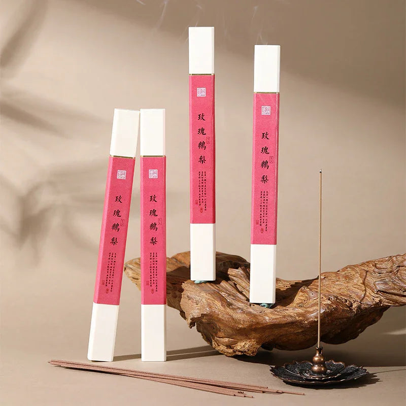 Rose and pear scented incense sticks with red packaging displayed on wood and lit in bronze holder