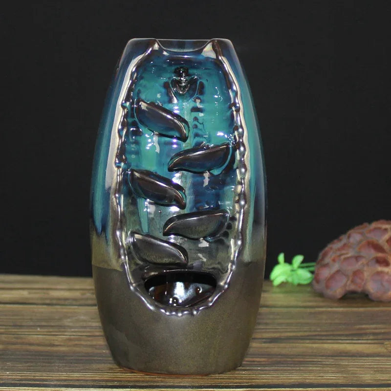 ceramic backflow incense burner with cascading leaf design on wooden table against black background