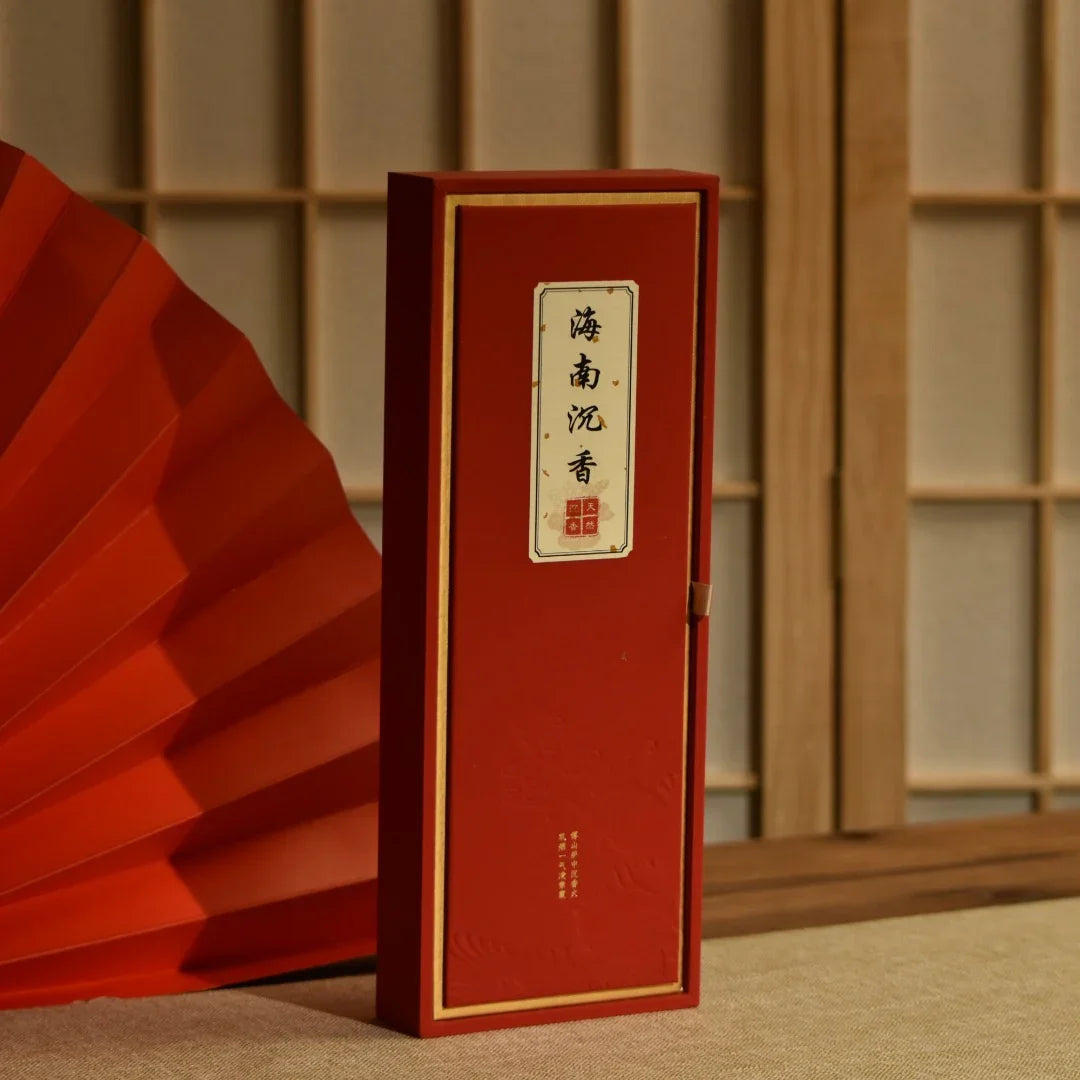 Red Chinese incense box with calligraphy label, traditional folding fan and wooden screen background