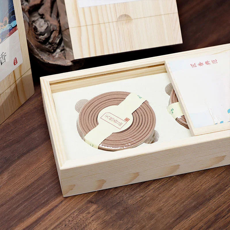 Wooden box containing coiled incense sticks with Japanese labels on a dark wooden table