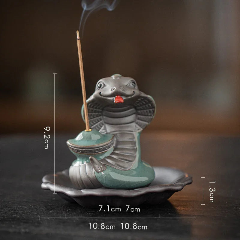 Ceramic cobra incense holder with burning stick, sitting on black dish with size dimensions