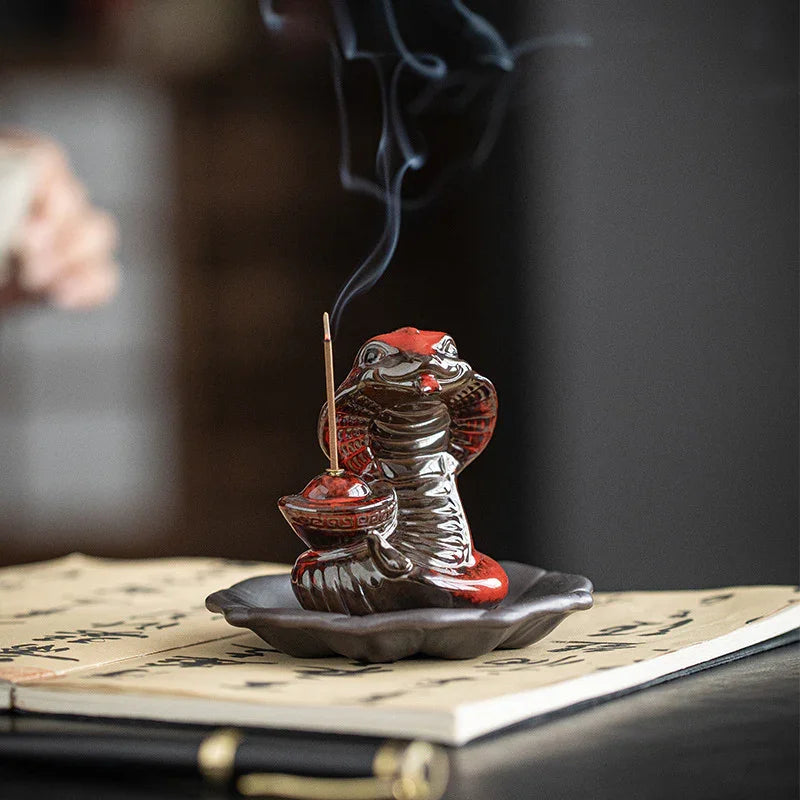 Ceramic cobra incense holder with burning incense stick and smoke on calligraphy paper