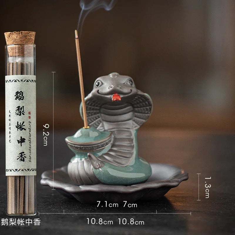 Ceramic cobra snake incense burner with smoke and incense sticks in glass jar on wooden surface