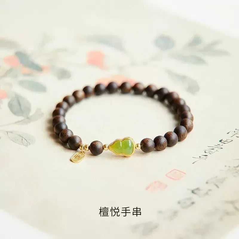 Elegant beaded bracelet with dark wooden beads and green jade centerpiece on textured paper