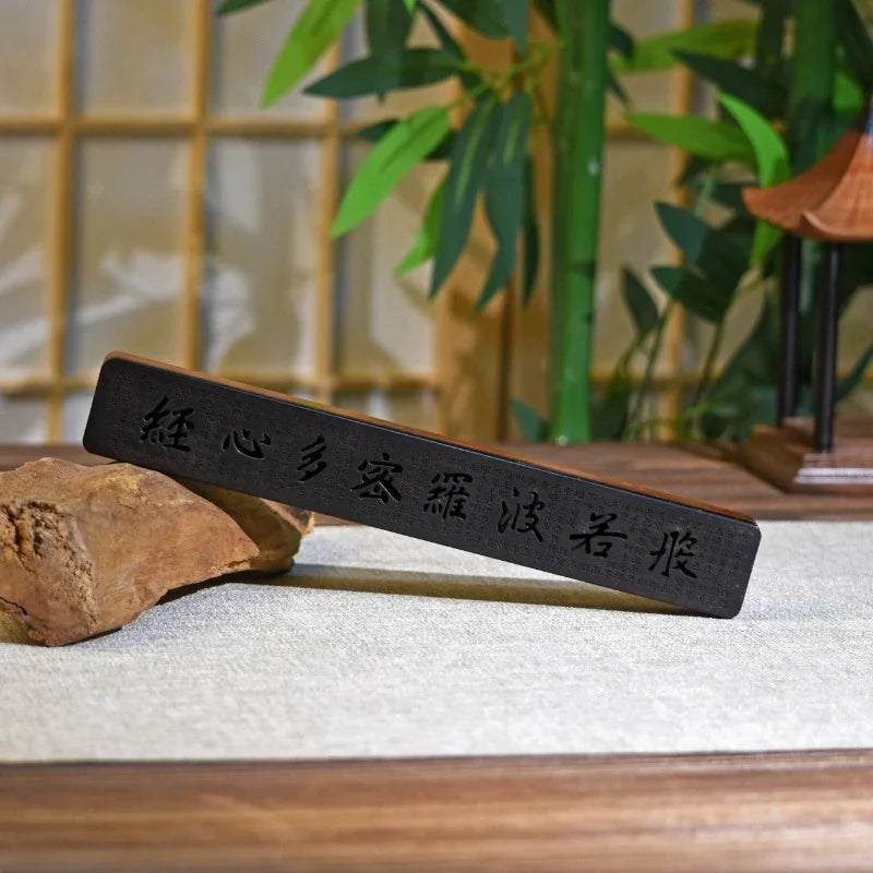 Chinese calligraphy wooden ink stick displayed on rocks with bamboo and traditional decoration background