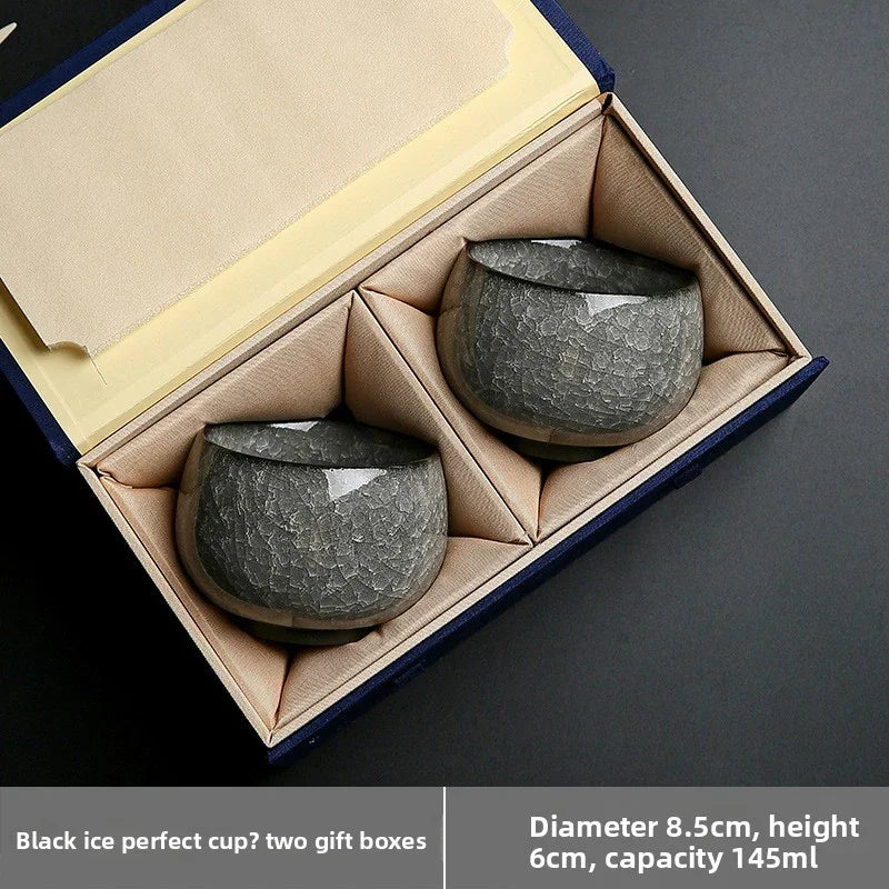 Two black textured ceramic cups in a beige cushioned gift box with navy exterior