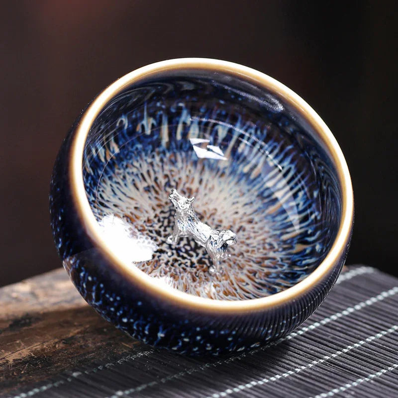 Glazed ceramic bowl with blue and brown patterns featuring a small silver wolf figurine inside