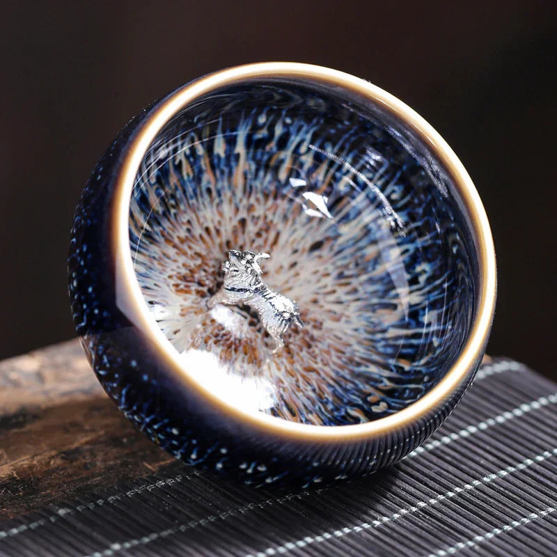 Close-up of a glossy ceramic bowl with a metallic dog figurine inside and intricate blue and beige patterns
