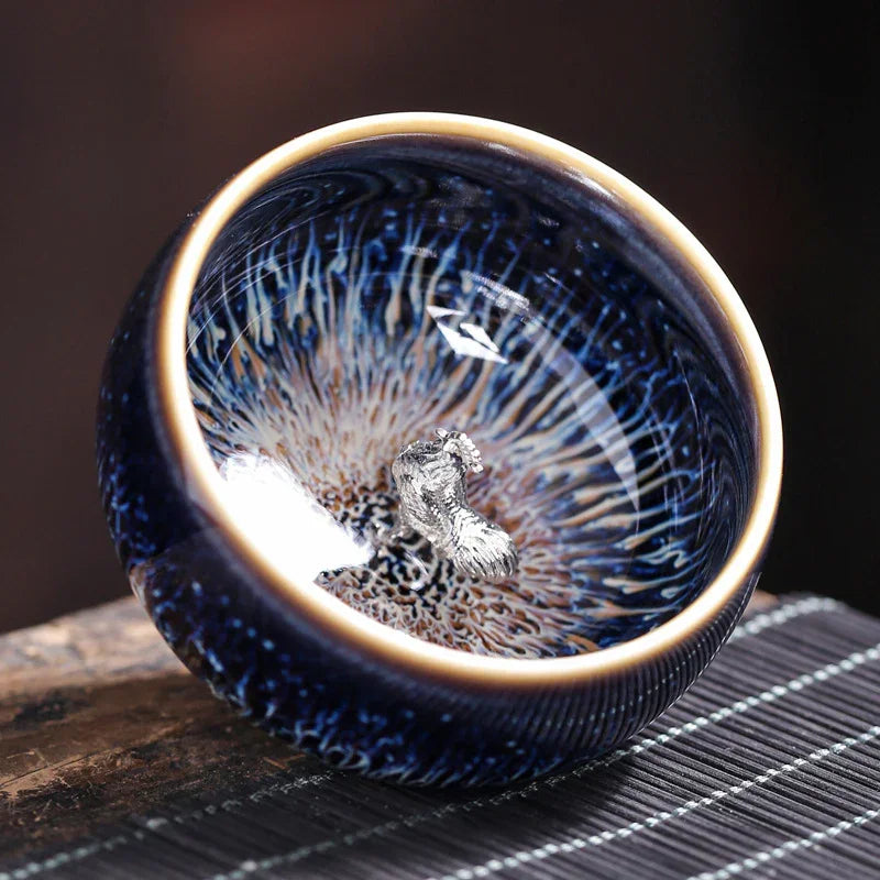 Glossy ceramic bowl with intricate blue and beige pattern and silver textured centerpiece on wooden surface