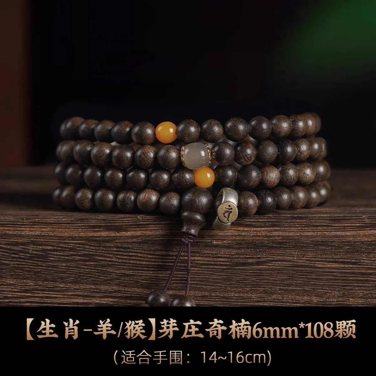 Dark wooden bead mala necklace with orange and translucent accent beads on a wooden surface