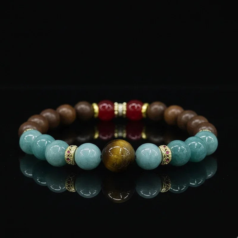 Beaded bracelet with polished blue, brown, red stones and gold-accented spacers on black reflection surface