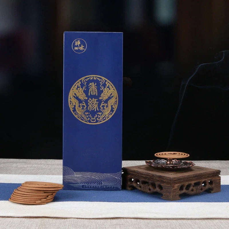 Blue box with gold dragon design next to wood incense holder with spiral incense burning