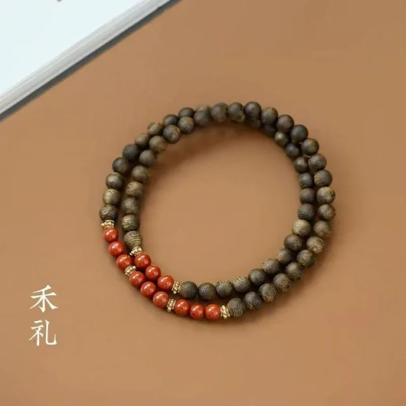 Wooden bead bracelet with red beads and gold accents on a brown surface