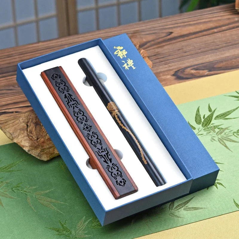 Elegant black and brown incense holder and black stick with gold dragon design in blue gift box on wooden table