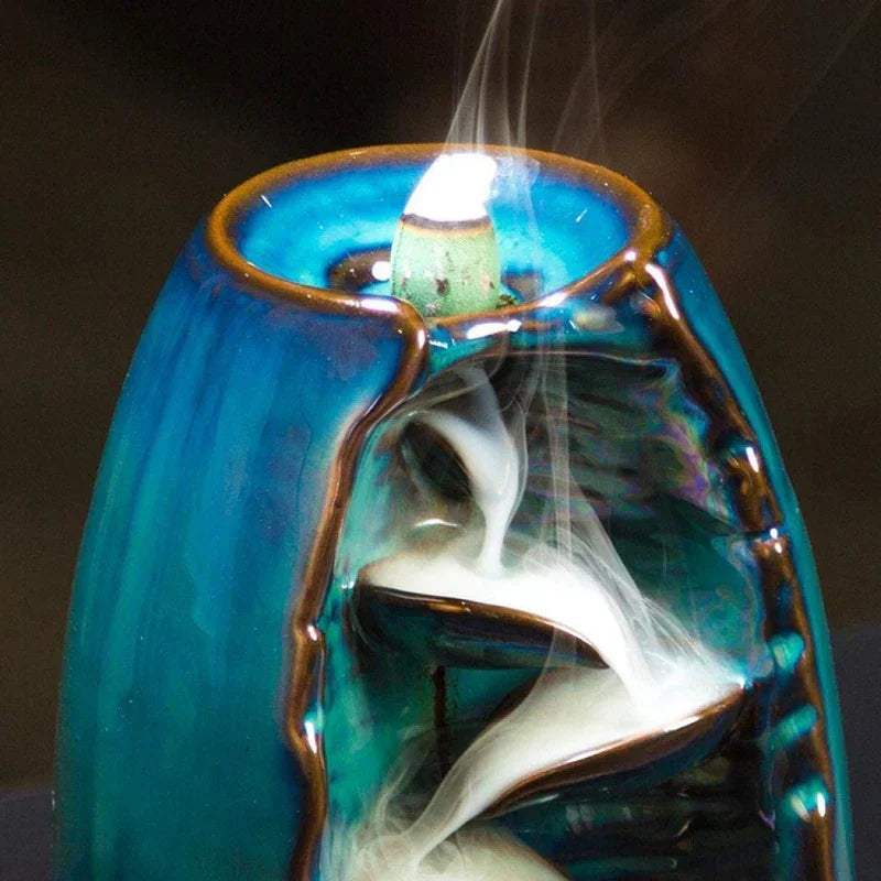 Blue ceramic backflow incense burner with white smoke flowing down spiral steps