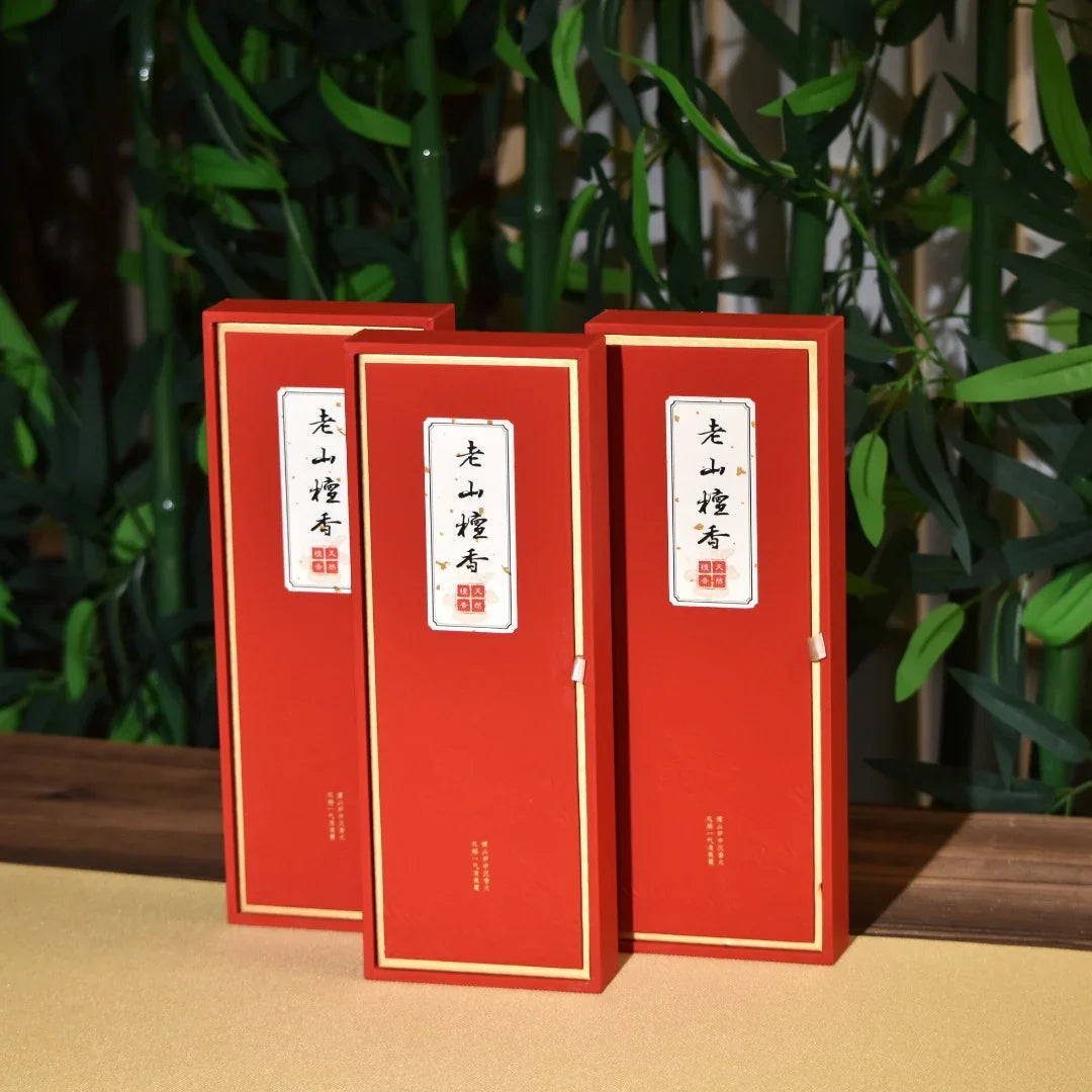 Three red rectangular incense packaging boxes with Chinese characters on white labels, set against bamboo background