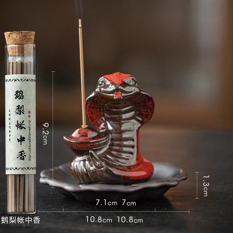 Elegant cobra-shaped incense holder with lit incense stick and glass tube of incense sticks on dark wooden surface