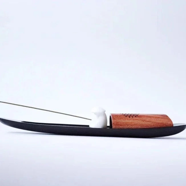 Minimalist black incense holder with a wooden cover and white ceramic mouse on white background