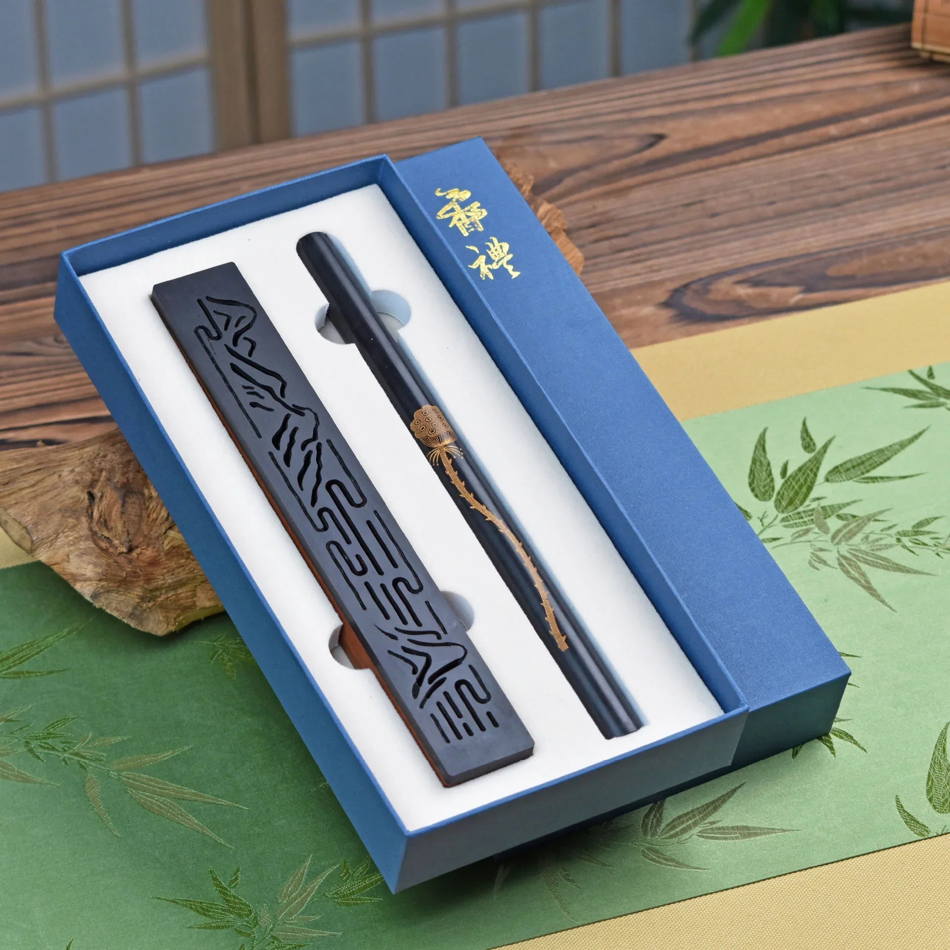 Traditional Chinese calligraphy brush and carved ink stick in a blue gift box on wooden table