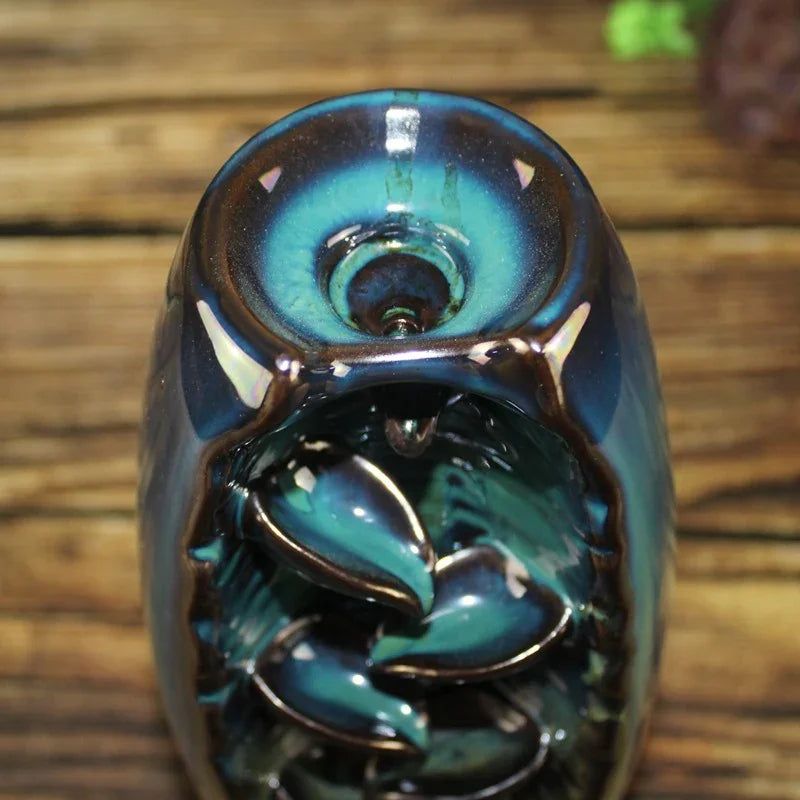 Glossy blue and teal ceramic essential oil burner on wooden table