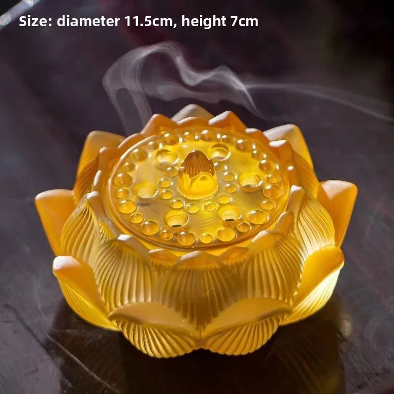 Yellow lotus-shaped glass incense burner with rising smoke on wooden surface