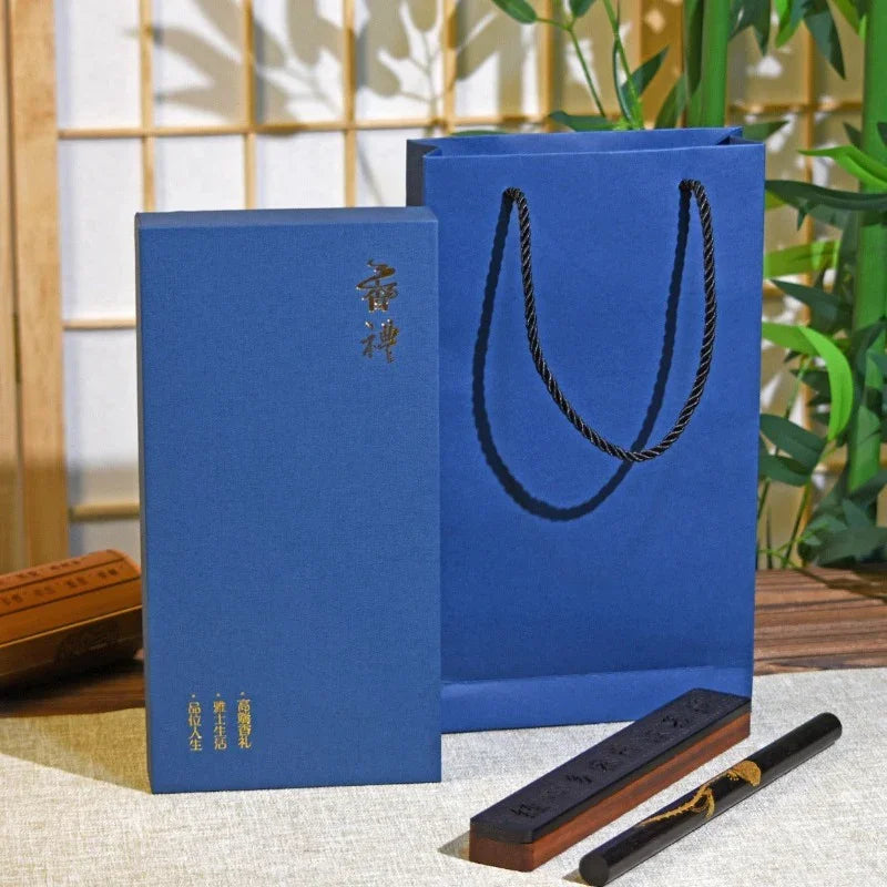 Elegant blue gift box and matching bag with Chinese characters, wooden ink stick and brush on table